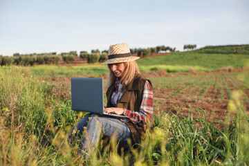 Female field engineer using computer in agricultural plantation. Integration of women in the field, agriculture and happy women concepts
