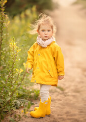 2 years old girl walking in the forest. Little girl portrait in yellow raincoat.