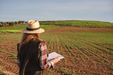 Female field engineer using a note book in agricultural plantation. Integration of women in the field, agriculture and happy women concepts