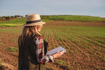 Female field engineer using a note book in agricultural plantation. Integration of women in the field, agriculture and happy women concepts