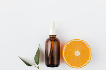 Orange essential oil in glass bottle with green leaf. Cosmetic concept