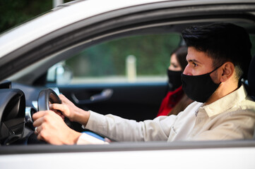 Young couple in a car wearing protective masks against covid 19 coronavirus pandemic
