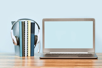 Fototapeta na wymiar Laptop. Mockup screen and headphones on wooden desk and plain background banner. Distant learning. working from home, online courses or support minimal concept. Notepads with headset