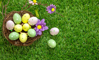 Fototapeta na wymiar Happy Easter. Colorful eggs in a nest on green grass, closeup view