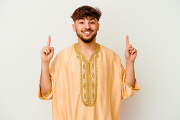 Young Moroccan man isolated on white background indicates with both fore fingers up showing a blank...