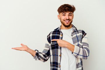 Young Moroccan man isolated on white background excited holding a copy space on palm.