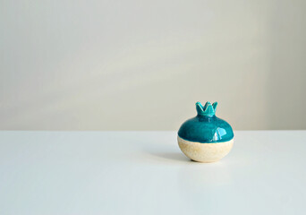 Turquoise vase in the form of a pomegranate on a white background, close-up. Stylish interior mockup, copy space.