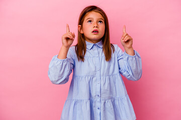 Little caucasian girl isolated on pink background  pointing upside with opened mouth.
