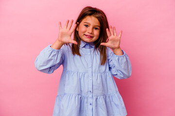 Little caucasian girl isolated on pink background  showing number ten with hands.