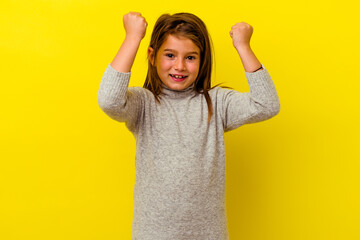 Little caucasian girl isolated on yellow background cheering carefree and excited. Victory concept.