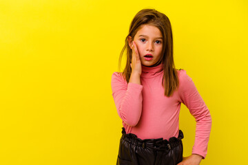 Little caucasian girl isolated on yellow background shouts loud, keeps eyes opened and hands tense.