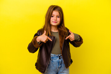 Little caucasian girl isolated on yellow background person pointing by hand to a shirt copy space,...