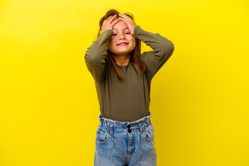 Little caucasian girl isolated on yellow background laughs joyfully keeping hands on head. Happiness concept.