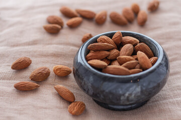 Roasted almonds. A handful of almonds in a plate. Cinnamon and orange. Top and side view