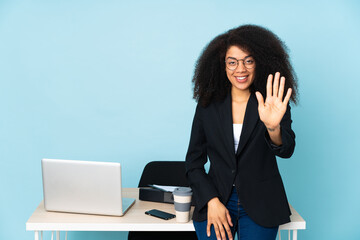 African american business woman working in her workplace counting five with fingers