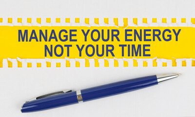 On the table are two sheets from a notebook and a pen on a yellow background written - MANAGE YOUR ENERGY NOT YOUR TIME