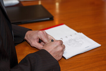 Ein Dokument wird beglaubigt, unterschrieben und mit dem Stempel best&auml;tig. Der Beamter hat einen Anzug an. Der Tisch ist braun, auf dem Tischen Dokumente, ein Buch.  Er ist  Standesbeamter.