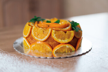 Homemade orange cake with sliced oranges in a kitchen