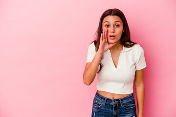 Young Indian woman isolated on pink background is saying a secret hot braking news and looking aside