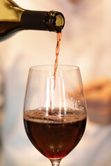 The process of bottling red wine into a glass by a waiter in a restaurant.
