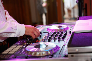 DJ macht gerade die Musik an, er dreht die Knöpfe, die Feier kann beginnen. Das Licht scheint...