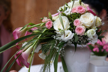 Ein Brautstrauß steht auf dem Tisch in einer grauen Vase, rosa und  weiße Farben