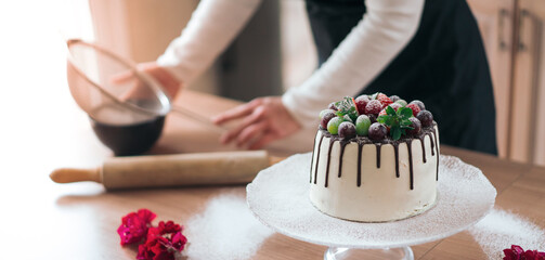 Young pastry chef cooking a delicious homemade chocolate cake with fruits in the kitchen