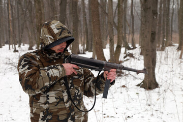 The man with vintage machine gun in the snowy forest