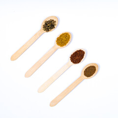 Seeds of beet, arugula, amaranth, mustard in wooden spoons on a white background. Place for an inscription. View from above.
