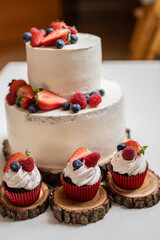 red cream cupcakes with strawberries and blueberries on natural wood coasters