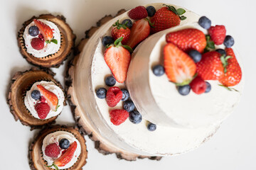 red cream cupcakes with strawberries and blueberries on natural wood coasters