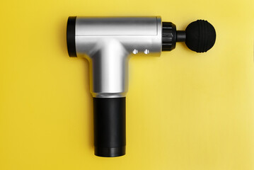 Massage percussion device on yellow background.