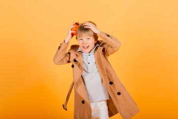 Shocked boy holding clock alarm, copy space. Kid isolated over yellow background. Time for school.