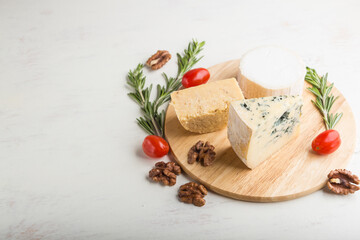 Fototapeta na wymiar Blue cheese and various types of cheese with rosemary and tomatoes on wooden board on a white background . Side view, copy space.