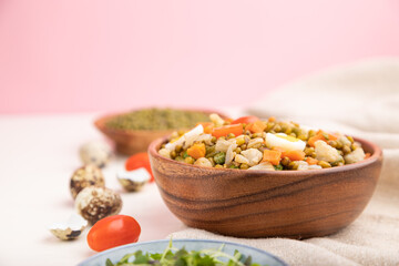 Mung bean porridge with quail eggs, tomatoes and microgreen sprouts on a white and pink background. Side view, selective focus, copy space.