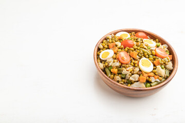 Obraz na płótnie Canvas Mung bean porridge with quail eggs, tomatoes and microgreen sprouts on a white wooden background. Side view, copy space.
