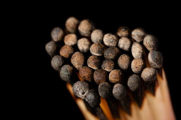 Burnt black matches in the shape of a heart on dark background. Love symbol