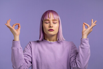 Calm woman with dyed purple hair relaxing, meditating. She calms down, breathes deeply with mudra...