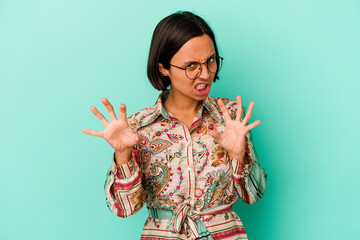 Young mixed race woman isolated on blue background upset screaming with tense hands.