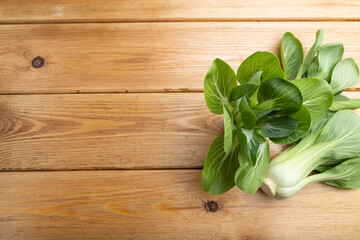 Fresh green bok choy or pac choi chinese cabbage on a brown wooden background. Top view, copy space.