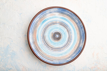 Empty blue ceramic plate on white concrete background. Top view.