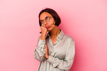 Young mixed race woman isolated on pink background tired of a repetitive task.