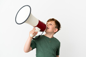 Little redhead boy isolated on white background shouting through a megaphone to announce something...