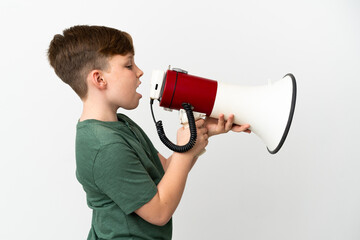 Little redhead boy isolated on white background shouting through a megaphone to announce something...
