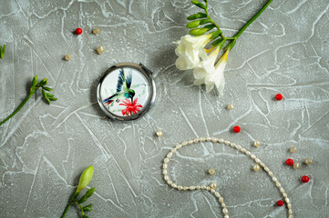 Top view of a feminine composition of flowers, beads and a small mirror. Flat lay with copy space