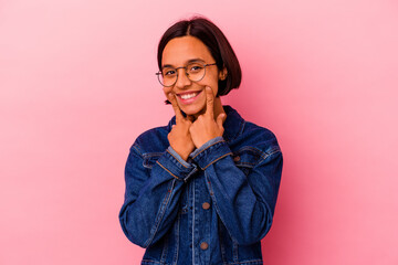 Young mixed race woman isolated on pink background doubting between two options.