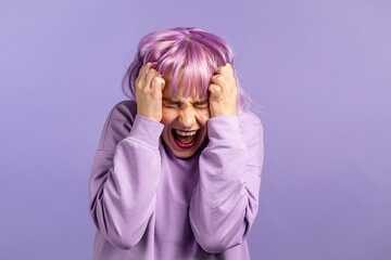 Frightened and screaming woman with dyed purple hair shocked isolated over violet background. Stressed and depressed pretty girl because of bad news.