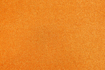 Orange yellow blurred background with fine texture of shiny crystals. Surface of glossy material