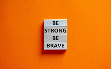 Be strong be brave symbol. Wooden blocks with words 'be strong be brave'. Beautiful orange background. Copy space. Motivational, business and strong brave concept.