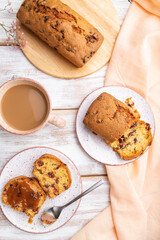Homemade cake with raisins, almonds, soft caramel and a cup of coffee on a white wooden background. top view, close up.